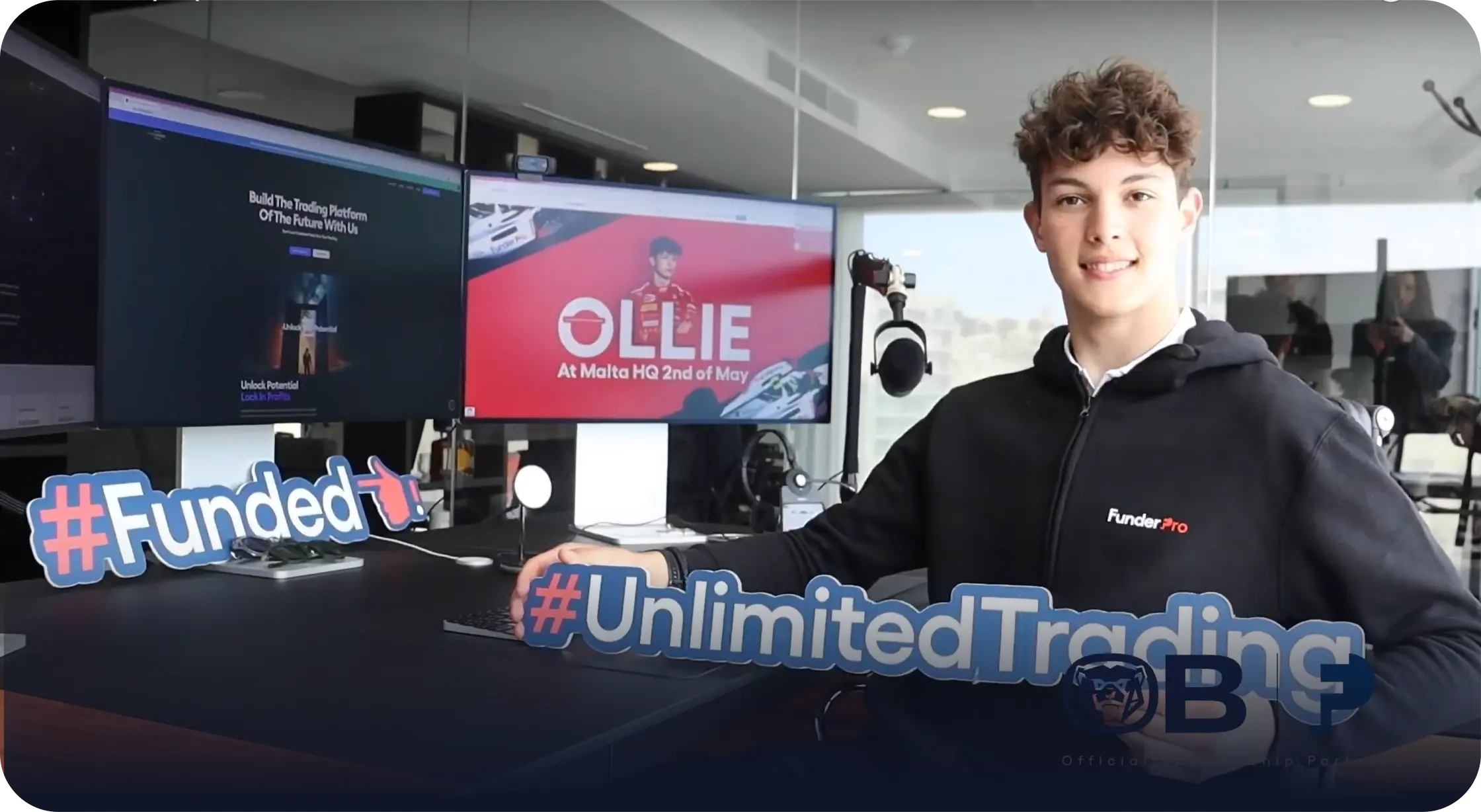 Ollie Bearman sitting at Owen Morton's desk at FunderPro HQ